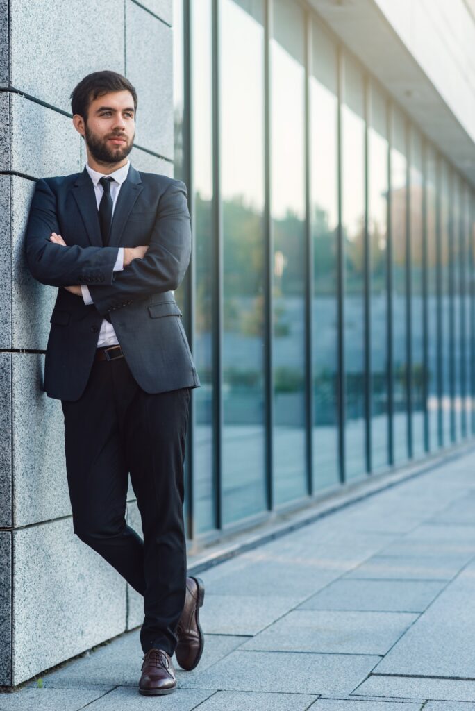 Full length portrait of young businessman with crossing hand in a suit