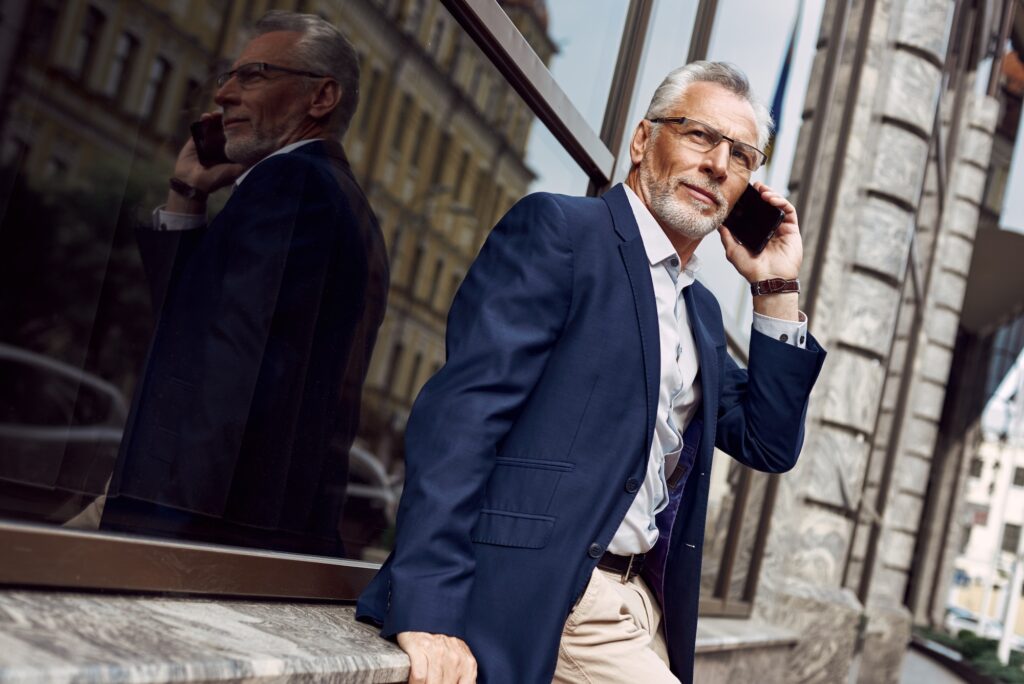 Successful businessman. Serious senior man in casual suit talking on the phone while walking